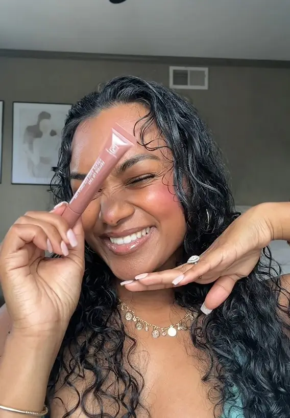 Woman holding Tina Mattern Hydrating Peptide Lip Tint featuring Shea Butter and Palmitoyl Tripeptide-1 for soft, hydrated, naturally tinted lips.